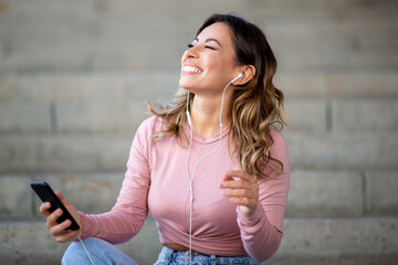 happy young woman listening to music with mobile phone and earbuds