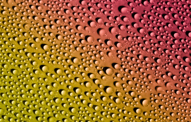 Water drops on glass as a background. Condensation on a cold drink. Multicolored background with drops texture.