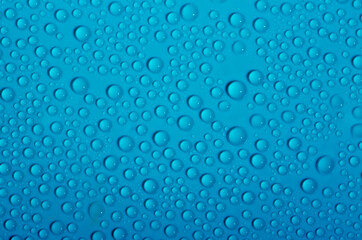 Fototapeta na wymiar Water drops on glass as a background. Condensation on a cold drink. Blue background with drops texture.