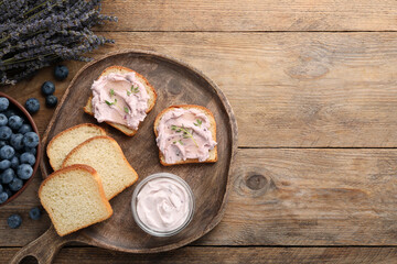 Fototapeta premium Tasty sandwiches with cream cheese, thyme and blueberries on wooden table, flat lay. Space for text