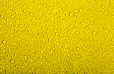 Water drops on glass as a background. Condensation on a cold drink. Yellow background with drops texture.