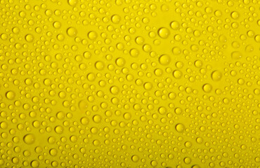 Water drops on glass as a background. Condensation on a cold drink. Yellow background with drops texture.