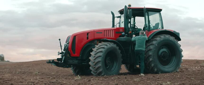 Hero shot portrait of 50s farmer walking towards tractor early in the morning in the field. Shot with 2x anamorphic lens