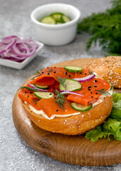 Vegan Carrot Lox served on bread bun with cream cheese, cucumber slices, red onion and dill. Tasty plant-based fish replacement to traditional lox made with strips of marinated carrots. Vertical.