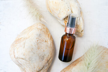 Glass dropper bottle with cosmetic oil, essential or serum with stones on white background, Natural organic spa cosmetics