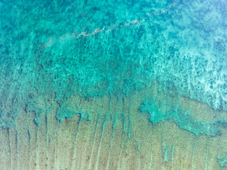 A large fringing reef grows along the edge of a remote island near Alor, Indonesia. This region is known for its high marine biodiversity and spectacular scuba diving and snorkeling.