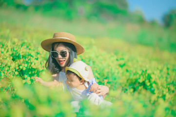 mother with little child in white blooming garden. woman with son in green leaves,happy family outdoors in spring