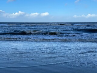Fototapeta na wymiar Wellen brechen sich im Sturm am Strand der Nordseeinsel Baltrum.