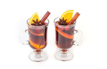 Traditional hot Christmas mulled wine with spices and oranges in mugs on a white background