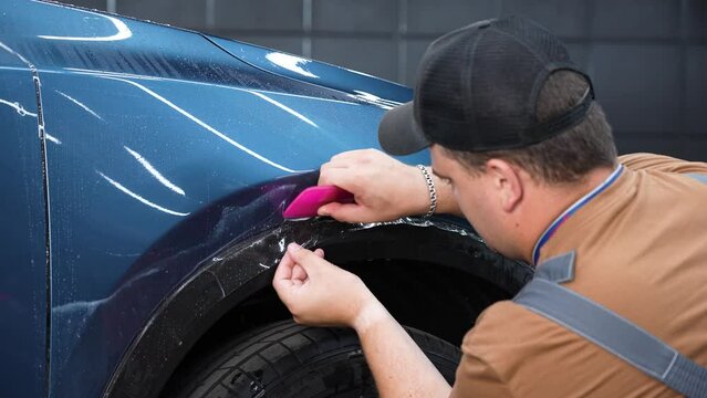 The master in the car service applies an armor film to the car. 