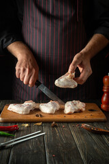 The chef prepares chicken nugget with raw chicken wings in the kitchen. Space for advertising on a dark background