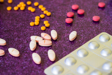 Medical bottles and medication pills spilling out on to purple background