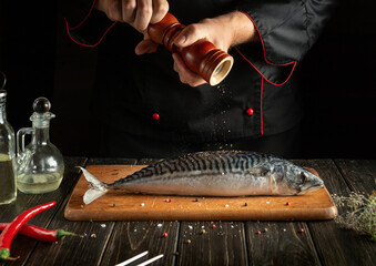 The cook prepares fresh mackerel in the kitchen. Scomber must be added with aromatic pepper before...