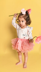 Niña latina con gerberas en la mano en fondo amarillo 