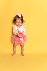 Niña en tutu y moño en la cabeza con una gerbera en la mano 