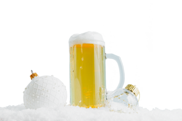 Mug of cold beer and two Christmas balls on the snow. Selective focus