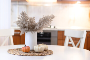 Modern kitchen with autumn seasonal decorations with fall dry flowers and pumpkins. Home kitchen interior decorated for Thanksgiving day. Close up.