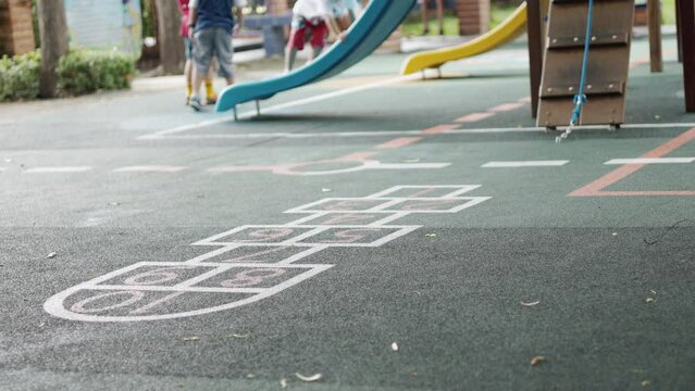 Blurred background with copy space of playground floor and seeing kindergarten kids who are playing with their friends at school shows concept of child recreation and activity with enjoyment.