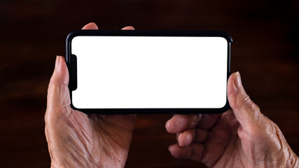 Old woman hands holds a smartphone with white empty screen for your mockup