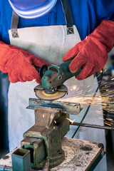 Worker grinding metal with a grinder and cleaning steel seam. Working in a metal