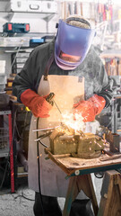 A man welder with safety helmet working with arc welding machine in the workshop