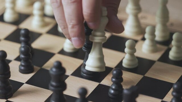 Close up and 4K of hand picking the king chess to kill the enemy king to win the game. It shows concept of competition with strategic business planning of teamwork for winning the battle.