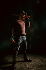 Evil in mask with chainsaw, horror Halloween scene in dark room