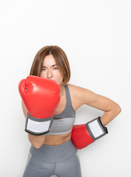 Young attractive female boxer in boxing gloves hitting on camera