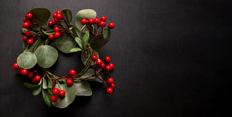 Christmas wreath decoration, blooming plant on black background, copy space