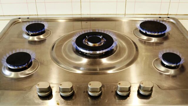 Gas cooker with burning flames of gas. Domestic kitchen with blue flames burning