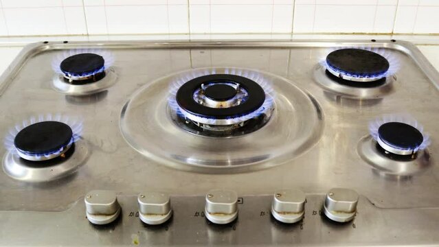 Gas cooker with burning flames of gas. Domestic kitchen with blue flames burning