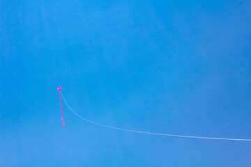 Pink kite flying with blue sky in Germany.