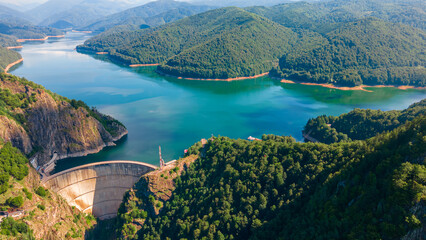 Aerial photography of Vidraru dam, in Romania. Photography was shot from a drone from above canyon at Vidraru lake with the dam and the lake in the view and mountains in the background.