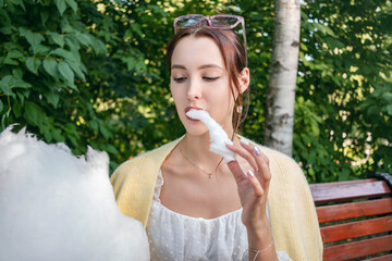 Fototapeta premium A girl eats cotton candy in a city park.