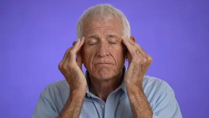 Portrait of sick ill tired elderly gray-haired man with headache 70s wears blue shirt rub head...