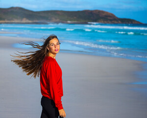 portrait of a beautiful long-haired girl on the famous lucky bay beach at sunset; happy girl on the...