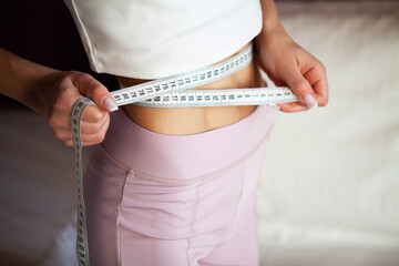 Woman with slim body measuring her waistline and torso