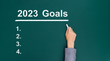 Businesswoman hand writing 2023 goals on blackboard