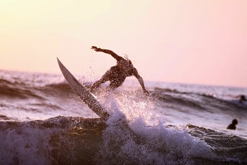 Man surfing the sea waves at sunset