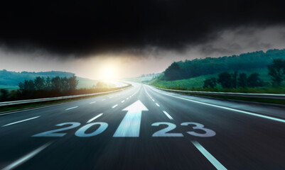 New year number 2023 and arrow sign on highway road against stormy clouds