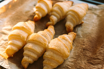 Freshly baked croissants with crispy crust on baking sheet