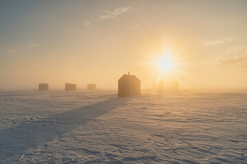 Socked in with fog at the ice fishing on a frozen harbor at sunrise in rural Prince Edward Island, Canada.