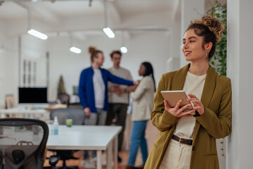 Attractive businesswoman standing in the office with a digital tablet in her hands