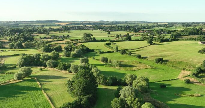 Aerial view flying backwards of valley in hilly countryside with small river Geul and grassland, Geuldal, Mechelen, Zuid Limburg, Netherlands