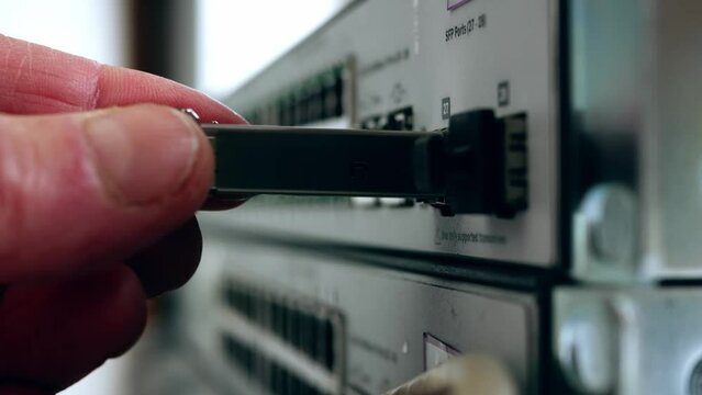 Network engineer connects fiber transceiver connection on computer switch