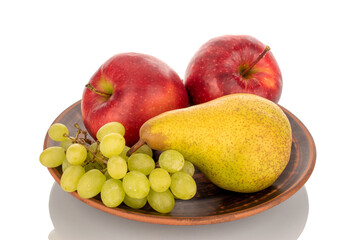 Two red apples, a pear and grapes on a clay plate, macro, isolated on a white background.
