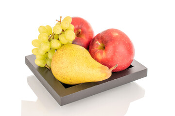 Still life of two red apples, a green pear and a branch of grapes on a black wooden plate, macro, isolated on a white background.