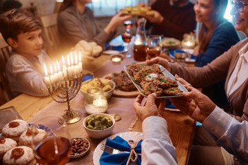 Close up of Jewish family having meal together at dining table on Hanukkah.