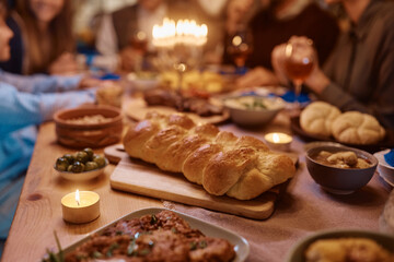 Challah bread on dining table with Jewish family in background.