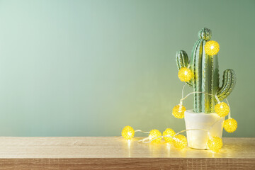 Christmas holiday greeting card with cactus as alternative Christmas tree and  lights garland on...